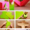 Una guía visual paso a paso que muestra el proceso de creación de una caja de regalo decorativa. Comienza con piezas planas de cartón y termina con una caja terminada en rosa y verde adornada con adornos florales, que ilustra perfectamente uno de los 65 Moldes para cajitas y manualidades escolares.