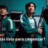 Proyecto Lúdico "Juego del Calamar PRIMARIA 1° - 6° NEM 22 Tres personas con chándal verde se encuentran de pie en un plató con unas escaleras metálicas de fondo. La escena está tenuemente iluminada y una persona sostiene el brazo de otra. El texto dice:
