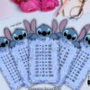 Cinco tarjetas de la tabla de multiplicar de Stitch con los números 5, 4, 10, 9 y 8, colocadas sobre un escritorio color pastel con flores, un cuaderno, gafas y un bolígrafo de fondo. También se ve un icono de PDF.