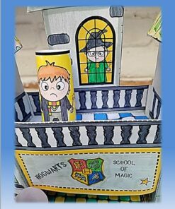 Una estructura artesanal de papel que se asemeja a una parte de la Escuela de Magia de Hogwarts, bellamente elaborada con detalles de Hogwarts 3D (Colorea, Recorta, Arma y Juega). Presenta un personaje de dibujos animados al frente, vestido con un uniforme de mago, y otro personaje en una ventana de arriba, vestido con una túnica verde y un sombrero de bruja. El escudo de Hogwarts se muestra con orgullo en la estructura 3D.