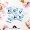 Seis tarjetas con un perro azul de dibujos animados y formas azules, etiquetadas en español como pentágono, óvalo, triángulo, círculo, rectángulo y cuadrado, están dispuestas sobre una superficie blanca con flores rosas.