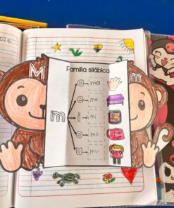 Una colorida hoja de trabajo con un mono recortado muestra la "Familia silábica" para la letra M, mostrando sílabas (ma, me, mi, mo, mu) con ilustraciones. El fondo muestra un cuaderno con garabatos y dibujos.