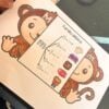 SILABARIO INTERACTIVO COMPLETO CON VOCALES 4 Una mano sostiene una hoja de ejercicios con un mono de dibujos animados y un cuadro titulado