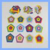 Pentágonos de papel de varios colores dispuestos en forma de cuadrícula, con figuras sueltas apiladas en la parte superior.