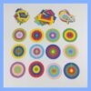 Doce diseños circulares de papel multicolor bajo tres montones de recortes de diversos colores.