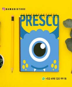 Un cuaderno de espiral azul con una portada de un monstruo tuerto de dibujos animados, titulado "PRESCO", se coloca sobre un fondo amarillo con un lápiz, un sello, una planta suculenta y hojas de eucalipto cerca. Se ven las redes sociales y la información de WhatsApp.