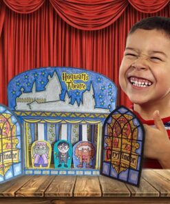 Un niño sonríe ampliamente mientras está parado detrás de un pequeño teatro de marionetas llamado 