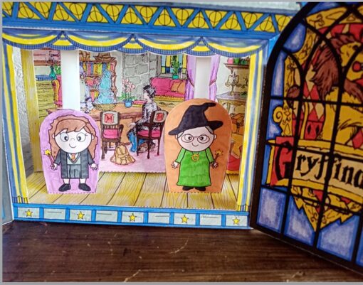 Un colorido diorama representa dos personajes dibujados de pie en el interior. Uno lleva un traje negro con gafas redondas y el otro un vestido verde con un sombrero de bruja. Al fondo se muestra una acogedora habitación con mesa y sillas que recuerda a Hogwarts. Una ventana tiene la palabra "Gryffindor". El nombre del producto es Teatro Guiñol Hogwarts.