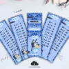 Cinco marcapáginas azules con las tablas de multiplicar del 1 al 5 y Bluey, el perro de dibujos animados, en la parte inferior. En el centro hay un icono de descarga y los marcapáginas tienen un diseño divertido con dibujos y huellas de patas.