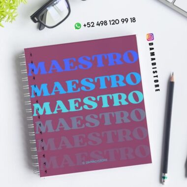 Un cuaderno de espiral con la palabra "MAESTRO" repetida en diferentes tonos de azul y morado en la portada. Cerca hay unas gafas negras, una planta verde, dos bolígrafos e información de contacto de DAMADISTORE.