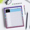 Agenda docente primaria 2025-2026 letras 17 Hoja de seguimiento de deberes encuadernada en espiral sobre un pupitre con un bolígrafo, gafas y un clip. La hoja tiene columnas para los nombres de los alumnos y las tareas. La información de contacto y