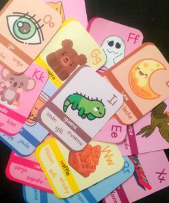 Una variedad dispersa de coloridas tarjetas del abecedario (Lectura de palabras) que muestran letras del alfabeto español, cada una acompañada de sus correspondientes ilustraciones y palabras. Las tarjetas presentan varios objetos y animales, como una iguana, un gofre y un koala.