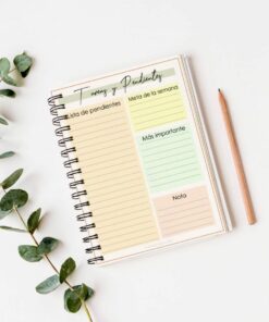 Sobre una superficie blanca hay un cuaderno de espiral con secciones de colores pastel etiquetadas como 