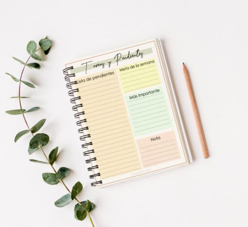 Sobre una superficie blanca hay un cuaderno de espiral con secciones de colores pastel etiquetadas como "Lista de pendientes", "Meta de la semana", "Más importante" y "Nota". Este Cuaderno de estudio - Dinosaurio (100 hojas) presenta un lindo motivo de dinosaurio, con un lápiz colocado al lado y una ramita de vegetación decorando el lado izquierdo.