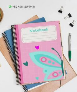Un Cuaderno de raya Mariposa PDF con una cubierta rosa con un diseño de Mariposa se encuentra encima de otros artículos de papelería, incluido un cuaderno azul y uno marrón. Hay un bolígrafo, dos clips para carpetas y una pequeña planta en una maceta cerca. Se ve un número de contacto de WhatsApp.