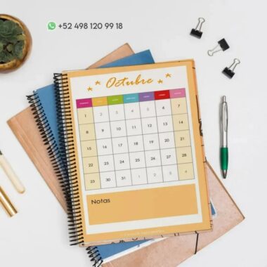 Un escritorio con un calendario encuadernado en espiral para octubre encima de varios cuadernos de raya Mariposa PDF. El calendario está codificado por colores y tiene espacio para notas en la parte inferior. También sobre el escritorio hay una planta, un bolígrafo turquesa, un bolígrafo blanco, un clip para carpetas y dos sujetapapeles. Arriba se muestra un número de teléfono.