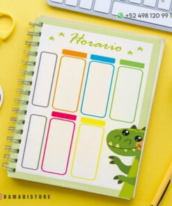 Un colorido planificador semanal con secciones etiquetadas en diferentes colores brillantes en un Cuaderno de raya con diseño dinosaurio PDF en espiral que presenta una linda ilustración de un dinosaurio verde. Rodeado de un fondo amarillo, un bolígrafo, un papel con un emoticón y un número de teléfono visible con un icono de WhatsApp.