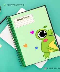 Un cuaderno de raya con diseño de rana encuadernado en espiral con una linda ilustración de rana y corazones coloridos en la portada se encuentra sobre una superficie verde. Está al lado de una pequeña maceta, un portátil blanco cerrado y un bloc de notas amarillo. Un número de contacto es visible en la parte superior y 