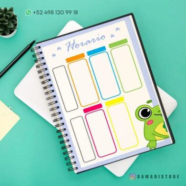 Un Cuaderno de raya con diseño de rana en la portada está abierto sobre un escritorio verde azulado. La página presenta una colorida plantilla de programación semanal denominada "Horario". Cerca, una pequeña planta en maceta y un estuche blanco con una nota adhesiva amarilla añaden encanto a la escena.