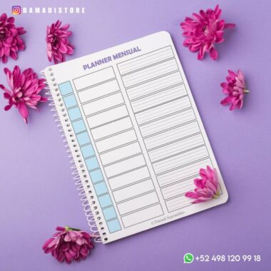 Una Agenda en color pastel 2024 se encuentra abierta sobre una superficie de color violeta pastel, rodeada de flores rosas. El planificador tiene un diseño para organizar días y tareas. En las esquinas se muestran el identificador de Instagram (@damadistore) y un número de teléfono con el símbolo de WhatsApp.