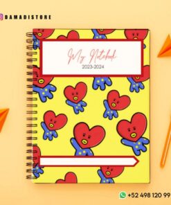 Un cuaderno de espiral amarillo con un patrón de corazón vibrante y caricaturesco en la portada, que recuerda a los diseños de BT21. La etiqueta dice 