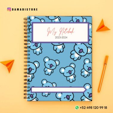 Un cuaderno encuadernado en espiral con cubierta azul que presenta un patrón repetido de lindas ilustraciones de koalas. El PDF del Paquete de cuadernos BT21 se titula "Mi Cuaderno 2023-2024". Alrededor del cuaderno se colocan dos aviones de papel naranja y un bolígrafo naranja sobre un fondo amarillo. La información de contacto y los identificadores de redes sociales también están presentes en la imagen.