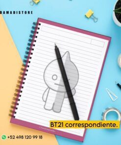 Vista superior de un escritorio con varios elementos, como un Cuaderno BT21 VAN con un personaje de dibujos animados, un bolígrafo negro, clips, una chincheta y una pequeña planta. El texto 
