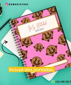 Un Cuaderno BT21 Shooky con una cubierta rosa con caras marrones caricaturescas, incluido Shooky de BT21, y con la etiqueta 
