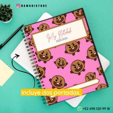 Un Cuaderno BT21 Shooky con una cubierta rosa con caras marrones caricaturescas, incluido Shooky de BT21, y con la etiqueta "Mi cuaderno 2023-2024" se encuentra sobre una superficie turquesa junto a una tableta blanca, una pequeña planta y notas adhesivas. El texto de la imagen dice "Incluye dos portadas" y se proporciona información de contacto.