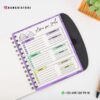 Cuaderno Descripción de Mis Libros leídos 15 Un Cuaderno abierto encuadernado en espiral Descripción de Mis Libros leídos yace sobre un escritorio junto a una suculenta verde. El planificador presenta un registro de lectura anual con los meses enumerados, incluidos enero, febrero y marzo, con espacios para libros leídos y seguimiento del progreso. La información de contacto está impresa en la parte inferior.