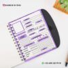Cuaderno Descripción de Mis Libros leídos 12 Un cuaderno abierto con espiral se encuentra sobre una superficie blanca junto a una planta suculenta y un bolígrafo. Las páginas del libro cuentan con una plantilla para Cuaderno Descripción de Mis Libros leídos con secciones para detalles como título, autor, calificación y comentarios, en una combinación de colores morado y blanco. La información de contacto y el identificador de redes sociales son visibles.