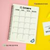 Agenda docente maestra 24-25 14 Un cuaderno de espiral se encuentra abierto en una página del calendario de octubre, con los días de la semana escritos en español (Domingo, Lunes, Martes, Miércoles). El cuaderno se coloca sobre un fondo rosa y amarillo. La información de contacto y una etiqueta geográfica para Instagram son visibles en la parte superior e inferior.