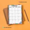 Un calendario de febrero encuadernado en espiral con bordes florales se encuentra abierto en un cuaderno de espiral marrón sobre un fondo naranja. Cerca se coloca un lápiz afilado con una goma de borrar azul. Contacto: +52 498 120 99 18. Usuario de Instagram: @damadistore.