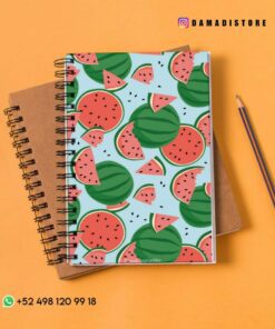 Un colorido cuaderno de espiral con un patrón de sandía en la cubierta se coloca encima de un cuaderno de espiral marrón. A la derecha hay un lápiz afilado. El fondo es una superficie suave, cálida y de color naranja. La imagen incluye información de contacto y identificadores de redes sociales.