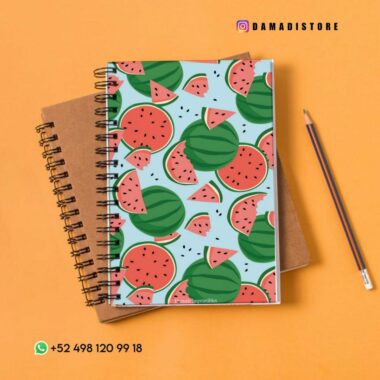 Un colorido cuaderno de espiral con un patrón de sandía en la cubierta se coloca encima de un cuaderno de espiral marrón. A la derecha hay un lápiz afilado. El fondo es una superficie suave, cálida y de color naranja. La imagen incluye información de contacto y identificadores de redes sociales.