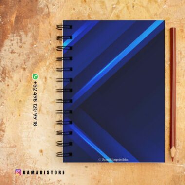 Un cuaderno de espiral azul con líneas geométricas se asienta sobre una superficie de color marrón claro. Hay un lápiz a la derecha del cuaderno. Hay datos de contacto e información de marca al lado del cuaderno. El identificador de Instagram @DAMADISTORE es visible en la esquina inferior izquierda.