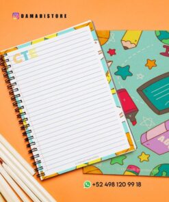 Vista superior de un colorido cuaderno de espiral con una página rayada abierta sobre una superficie de color naranja brillante. Cerca hay un juego de lápices blancos y un libro con tapa verde con varias ilustraciones coloridas. La información de contacto y un identificador de Instagram son visibles en la imagen.
