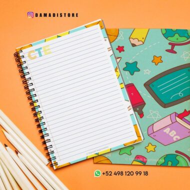 Vista superior de un colorido cuaderno de espiral con una página rayada abierta sobre una superficie de color naranja brillante. Cerca hay un juego de lápices blancos y un libro con tapa verde con varias ilustraciones coloridas. La información de contacto y un identificador de Instagram son visibles en la imagen.