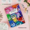 Cubierta de cuaderno con coloridos personajes animados, cada uno de los cuales expresa diferentes emociones. El cuaderno se encuentra sobre una superficie blanca, cerca de elementos decorativos como cintas, una maceta y un adorno de cristal. La información de contacto y un identificador de redes sociales se muestran arriba.