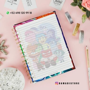 Un cuaderno de espiral con personajes de la película "Inside Out" en la portada se coloca sobre una superficie rosa, rodeado de elementos decorativos como cintas, una flor, un adorno brillante y un lápiz. La información de contacto y un identificador de redes sociales son visibles en el fondo.