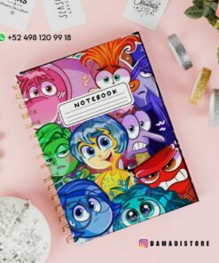 Cubierta de cuaderno con coloridos personajes animados, cada uno de los cuales expresa diferentes emociones. El cuaderno se encuentra sobre una superficie blanca, cerca de elementos decorativos como cintas, una maceta y un adorno de cristal. La información de contacto y un identificador de redes sociales se muestran arriba.