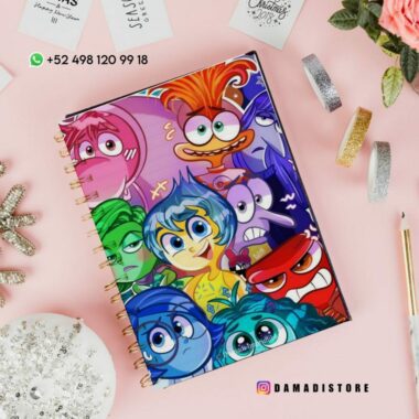 Sobre una superficie plana se coloca un cuaderno de espiral con una cubierta colorida con personajes de la película animada "Inside Out". Alrededor del cuaderno hay varios elementos estacionarios. También son visibles el identificador de Instagram "@damadistore" y un número de contacto de WhatsApp.