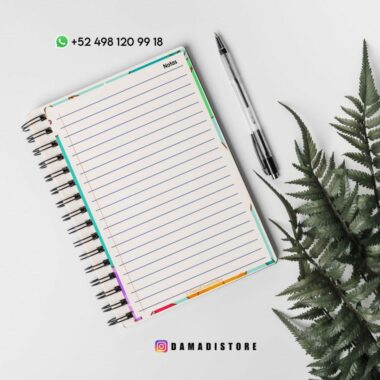 Un cuaderno encuadernado en espiral con papel rayado está abierto sobre una superficie blanca. Al lado del cuaderno hay un bolígrafo negro y al lado una hoja de helecho verde. En la parte superior, se muestra un número de teléfono con el logotipo de WhatsApp y en la parte inferior tiene un identificador de Instagram @damadistore.