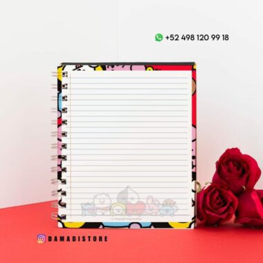 Un cuaderno encuadernado en espiral con coloridos personajes de dibujos animados en la portada se abre para revelar páginas rayadas. Se coloca sobre una superficie roja con dos rosas rojas al lado. Los detalles de contacto son visibles arriba y el identificador de Instagram "@damadistore" está impreso en la parte inferior.