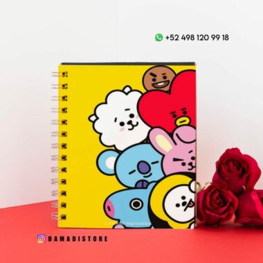 Un colorido cuaderno de espiral con personajes de dibujos animados en la portada, con varias caras de animales en tonos amarillo, rojo, azul y blanco. En el lado derecho se colocan tres rosas rojas y en la parte superior se muestra un número de contacto con un ícono de WhatsApp.