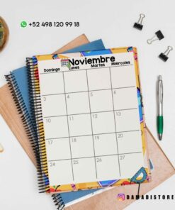 Un calendario de noviembre de 2023 se encuentra encima de cuadernos de espiral junto con varios suministros de oficina, incluidos un bolígrafo, un lápiz, una planta, sujetapapeles y clips. El calendario presenta un borde colorido y detalles de contacto, incluido un número de teléfono y identificadores de redes sociales.