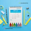 Calendario de espiral para abril de 2025 sobre fondo azul, rodeado de material de oficina como un lápiz, clips y notas adhesivas. Una fila de crayones de colores aparece en la parte inferior. Los datos de contacto y el logotipo aparecen en la parte superior e inferior.