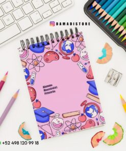 Un espacio de trabajo colorido incluye un cuaderno con ilustraciones escolares, como globos terráqueos y átomos, sobre una cubierta rosa, rodeado de lápices de colores, un sacapuntas, virutas de lápiz y un teclado. La información de contacto se muestra en la parte inferior.