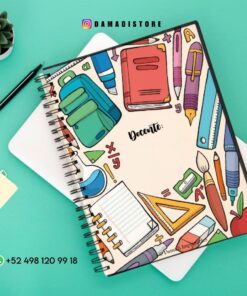 Cuaderno espiral colorido sobre fondo verde azulado, con ilustraciones de útiles escolares como libros, lápices, reglas y un pincel en la portada. Un número de teléfono visible en la parte inferior.