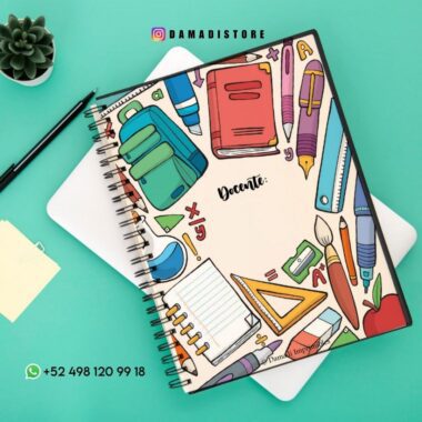 Cuaderno espiral colorido sobre fondo verde azulado, con ilustraciones de útiles escolares como libros, lápices, reglas y un pincel en la portada. Un número de teléfono visible en la parte inferior.